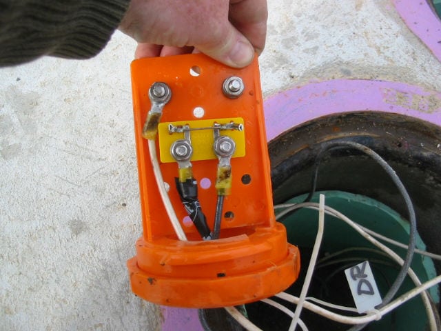 A person holding an orange device with wires attached.